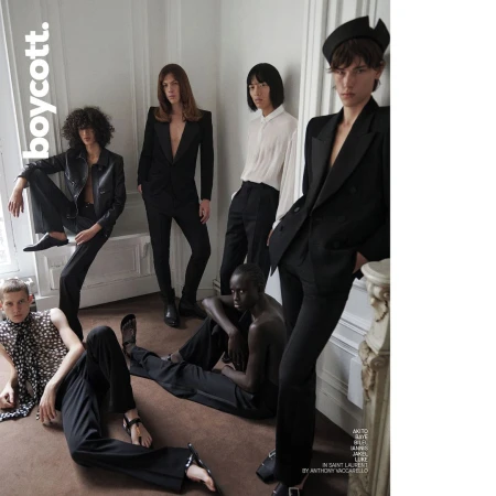 Editorial fashion shot of six models in a photo studio wearing black and white clothing, striking poses against a plain white wall.