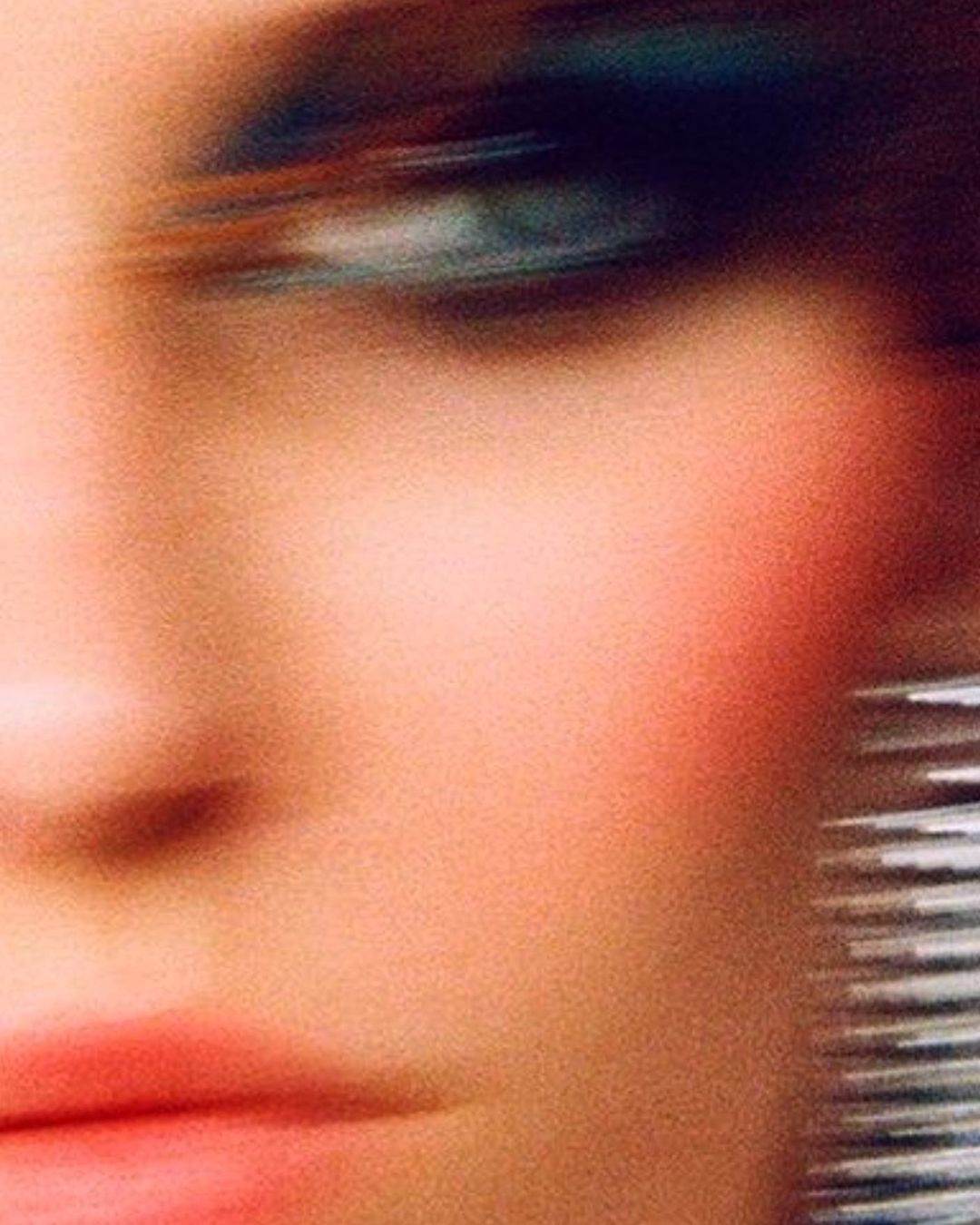 Close-up portrait of a woman with motion blur, vibrant blue eyeshadow, and pink lipstick photographed by Branislav Simoncik in Paris.
