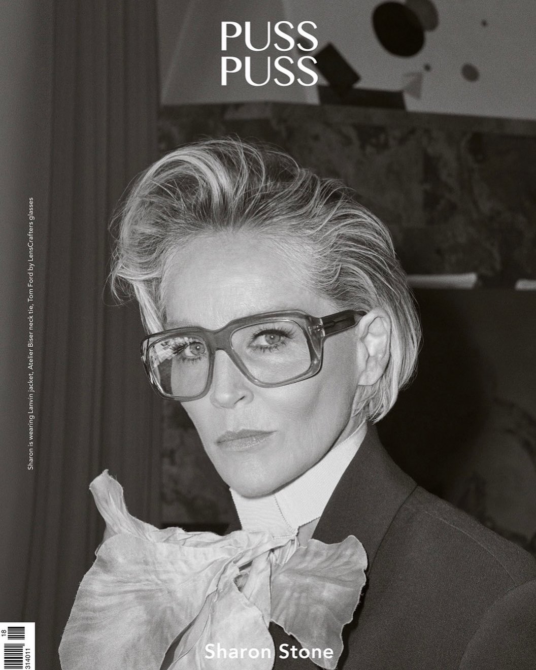 Black-and-white portrait of Sharon Stone wearing glasses and a suit with a large ruffled bow on a magazine cover.