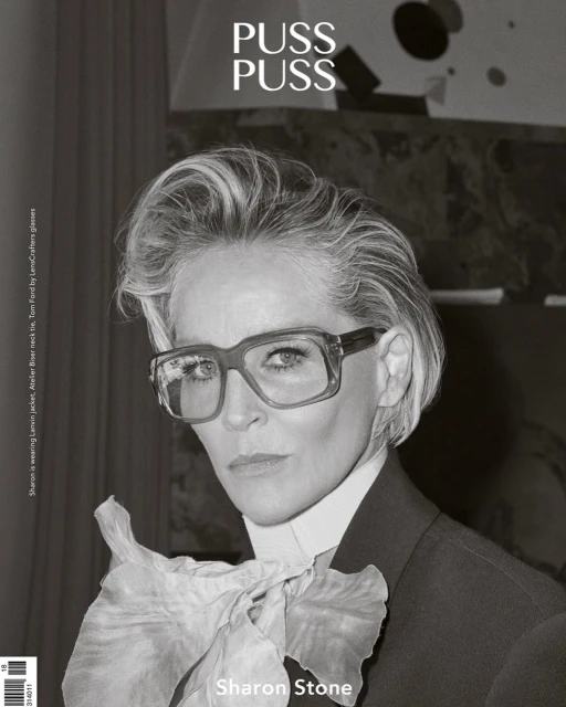 Black-and-white portrait of Sharon Stone wearing glasses and a suit with a large ruffled bow on a magazine cover.