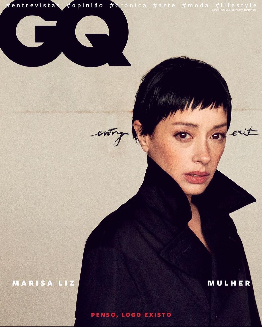 Magazine cover of GQ featuring Marisa Liz, with black short hair and a dark coat, against a beige backdrop with black handwritten text.