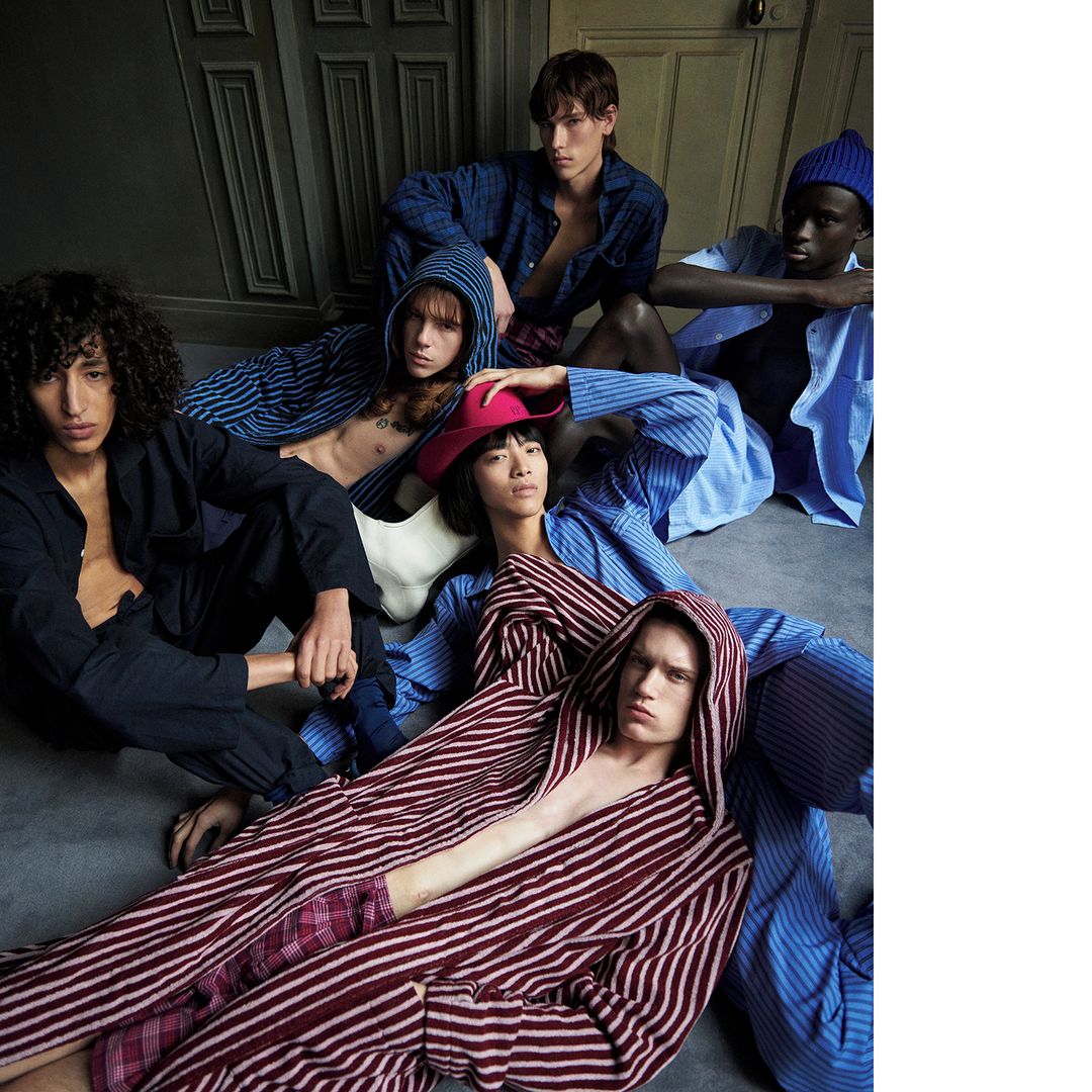 Group of six diverse young adult fashion models in various striped loungewear outfits indoors against a neutral wall and floor.