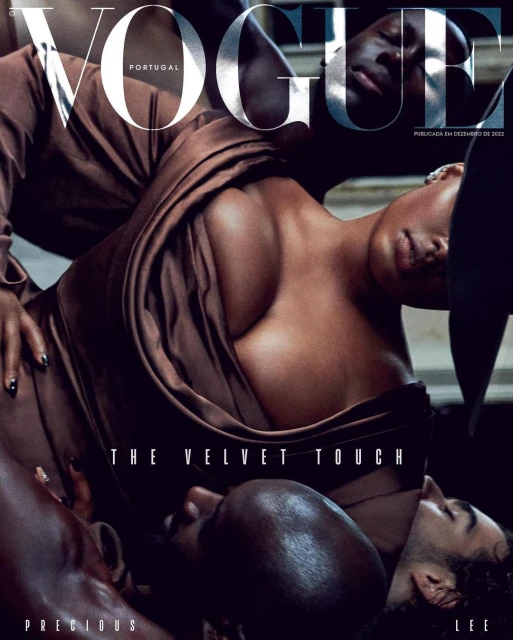 Vogue Portugal cover featuring a Black woman in a brown dress, surrounded by two men, against a dark background in a studio.