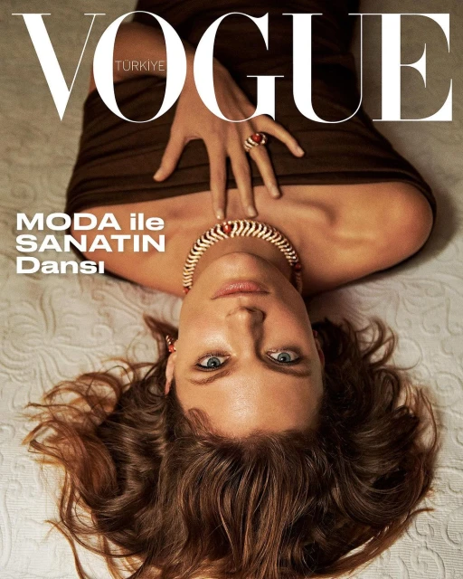 Vogue Turkiye cover featuring a model with brown hair lying on a textured surface wearing a brown top and ornate necklace and ring.
