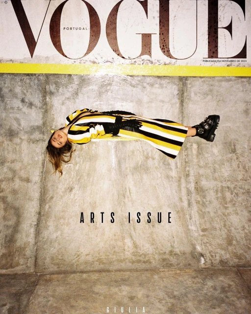 Vogue Portugal magazine cover featuring a woman in a yellow and black striped dress, lying on a concrete surface, with 'Arts Issue' text.