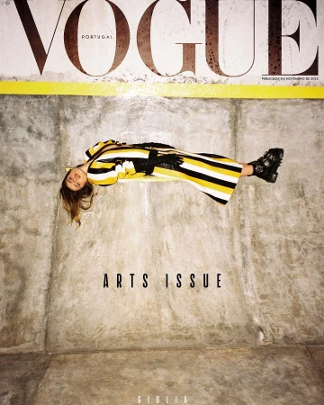 Vogue Portugal magazine cover featuring a woman in a yellow and black striped dress, lying on a concrete surface, with 'Arts Issue' text.