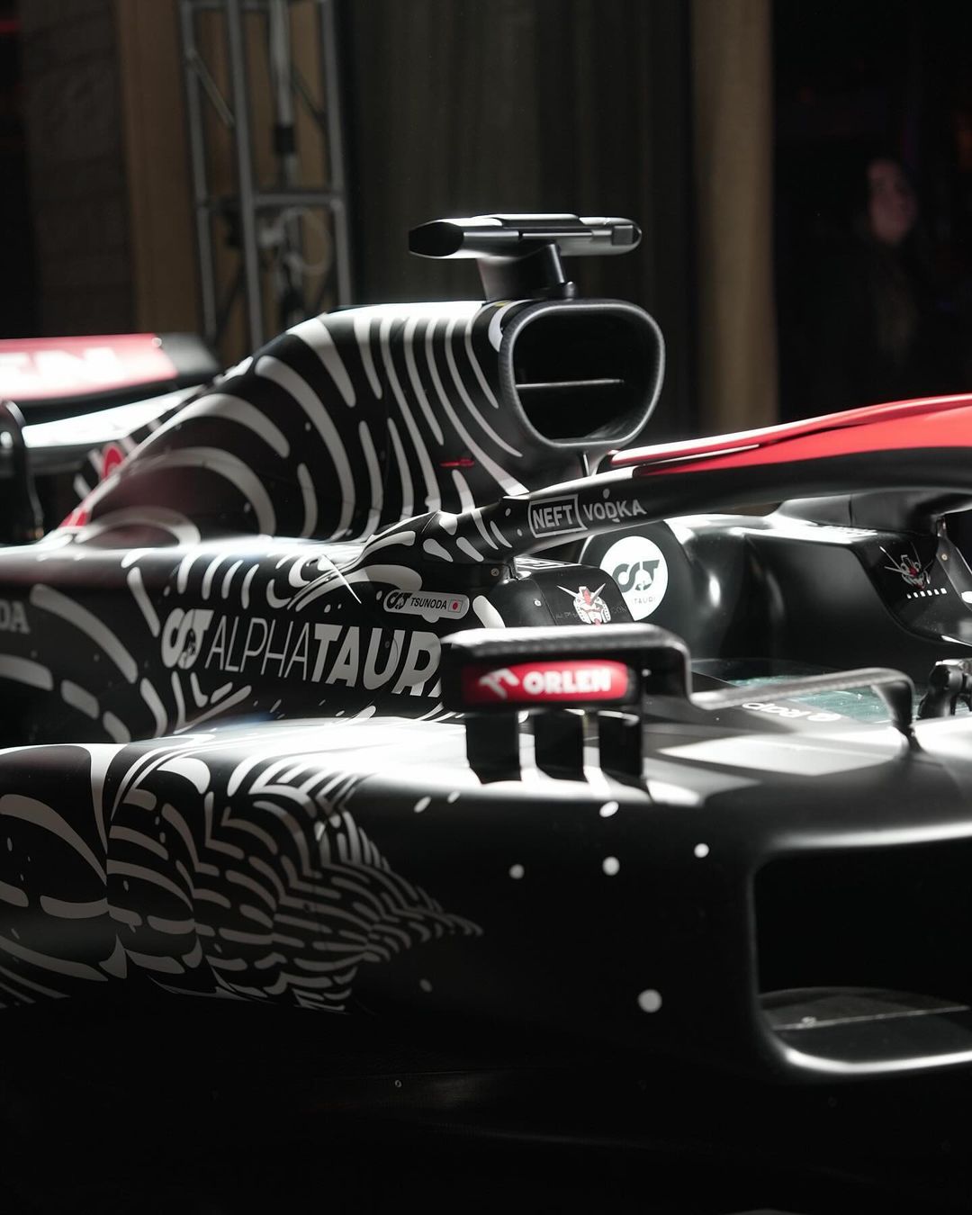 Close-up of a black and white AlphaTauri Formula 1 race car with sponsor logos, showcasing aerodynamic details and modern racing technology.
