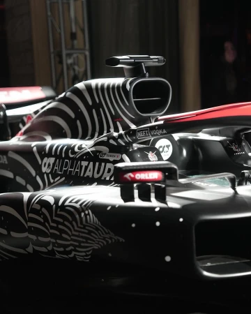 Close-up of a black and white AlphaTauri Formula 1 race car with sponsor logos, showcasing aerodynamic details and modern racing technology.