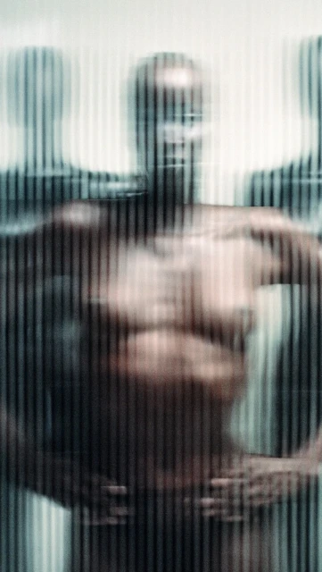 Distorted view of a group of figures in front of a vertically striped background, using blurred focus and strong contrasts.