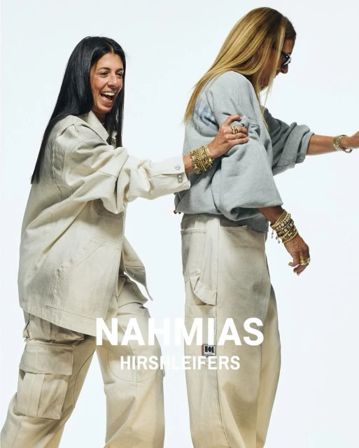 Two stylish women pose in a bright photo studio, showcasing beige and gray casual outfits with gold jewelry for a fashion advertisement.