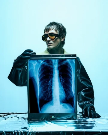 Adult holding chest x-ray in modern medical scene. Stylish eyeglasses and gloves add a contemporary fashion aesthetic.