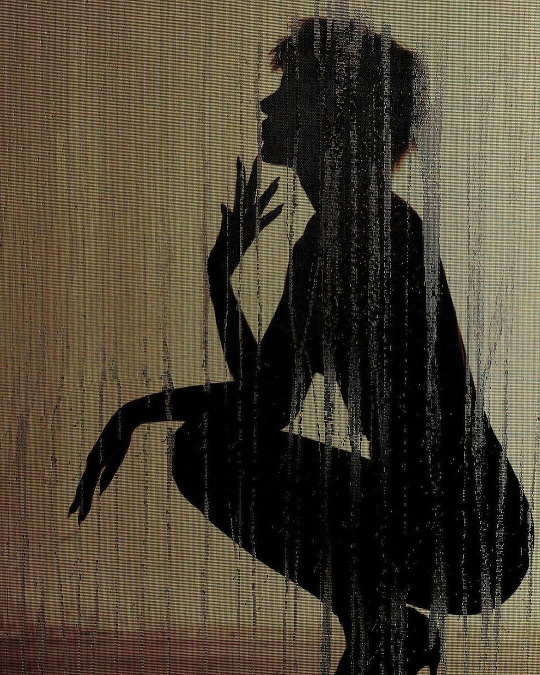 Silhouette of an adult female crouching in high heels, hand to face in a studio-like environment with an abstract background pattern.