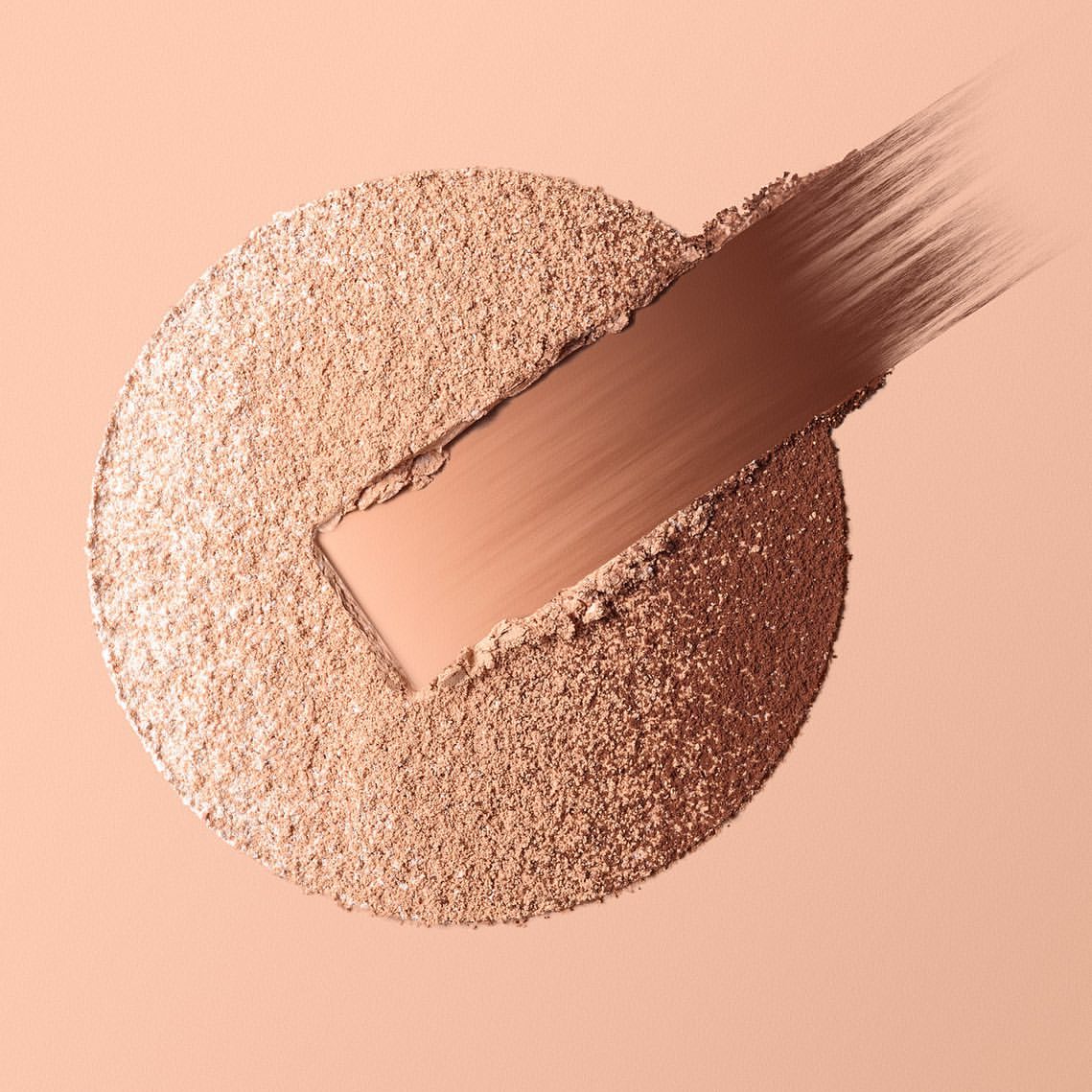 Close-up of beige powder foundation with a darker stripe of pressed bronzer or shadow applied diagonally across the surface.