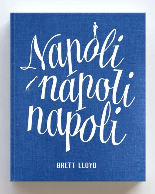 Close-up of the cover of the book Napoli 'napoli napoli' by Brett Lloyd, featuring white calligraphic text on a blue textured background.