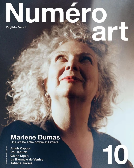 Magazine cover featuring an up-angle portrait of a smiling woman with voluminous gray hair, against a dark backdrop with diffused light.