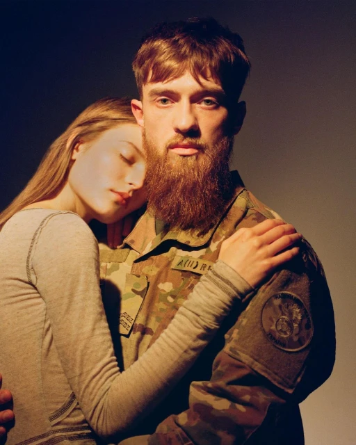 Portrait of a red-haired man in military camouflage embracing a blonde woman in a dimly lit indoor space, highlighting their connection.