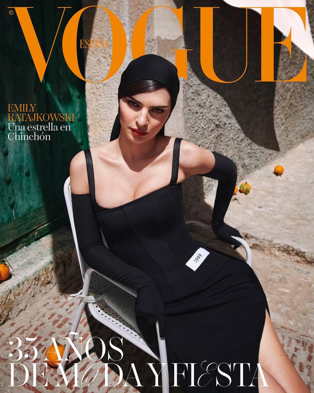 Vogue España cover featuring Emily Ratajkowski in a black dress, headscarf, and gloves sitting on a white chair outdoors.