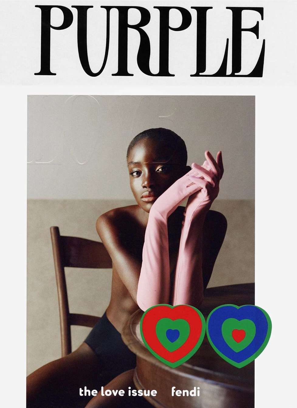 Magazine cover featuring a dark-skinned model wearing opera gloves, sitting at a table with two heart-shaped stickers.