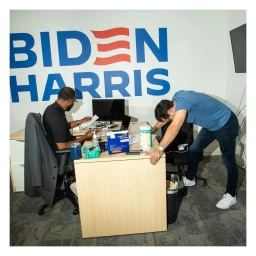 Two men working in a campaign office with large Biden Harris wall signage by photographer Brian Finke.