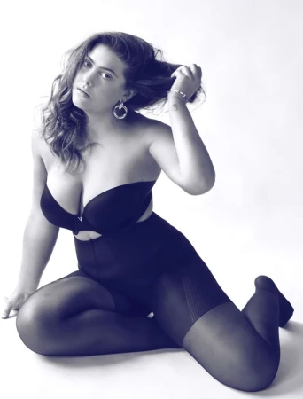 Plus size woman in black lingerie and stockings posing on a white studio background, photographed by Brian Sassmann.
