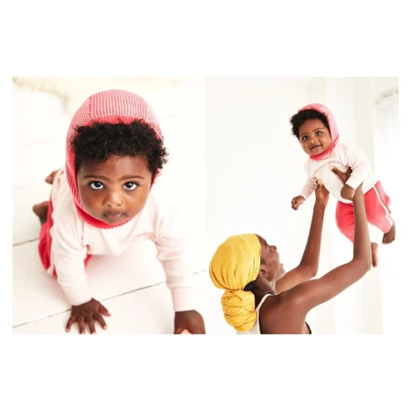 Two images show a Black baby crawling with a pink bonnet and sweater, and an adult female holding the baby in the air.