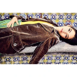 Model lying on tiled ledge wearing brown velvet jacket and green skirt, photographed by Brian Sassmann.