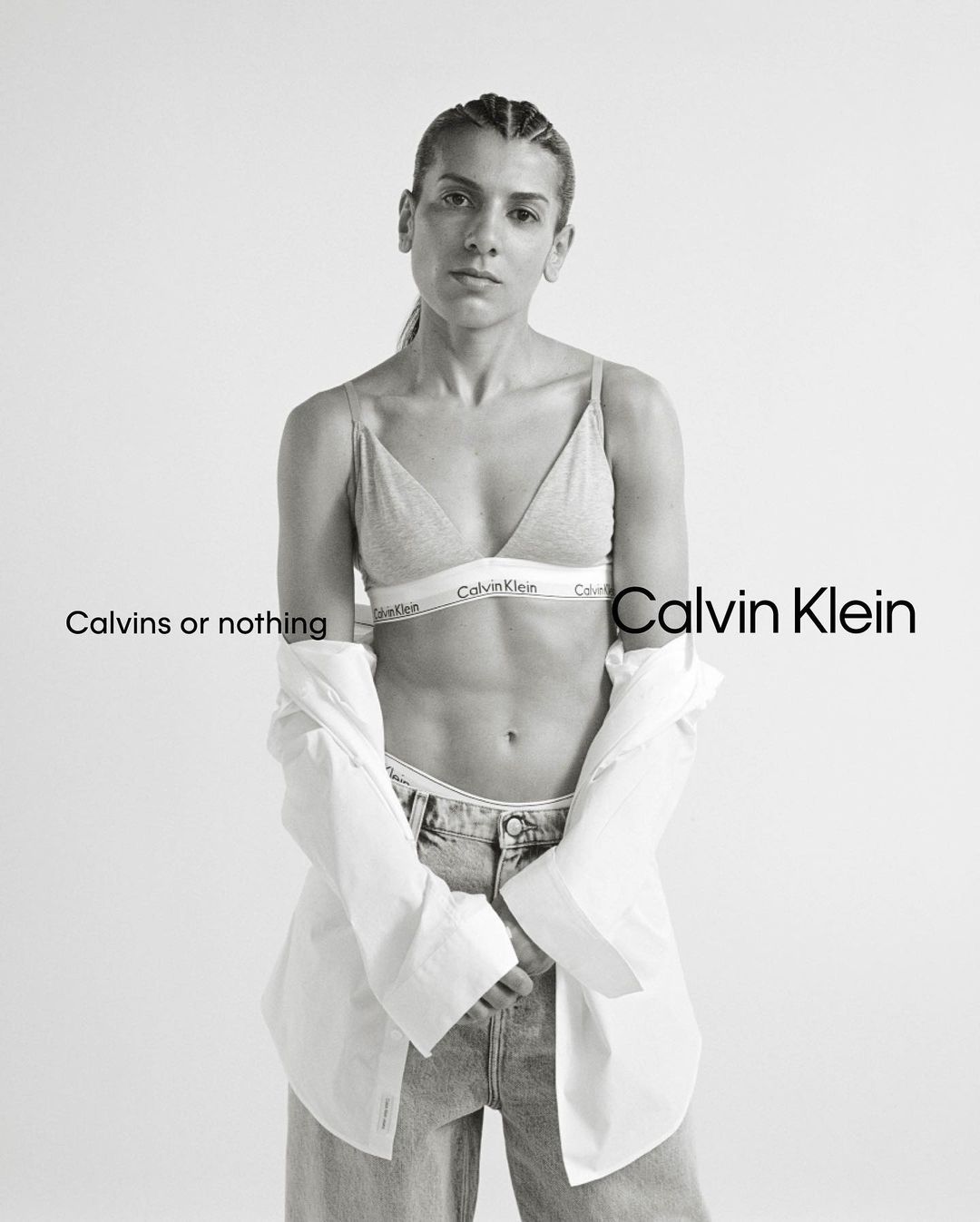 Black and white portrait of a woman wearing a bralette and unbuttoned white shirt, photographed by Brianna Capozzi.