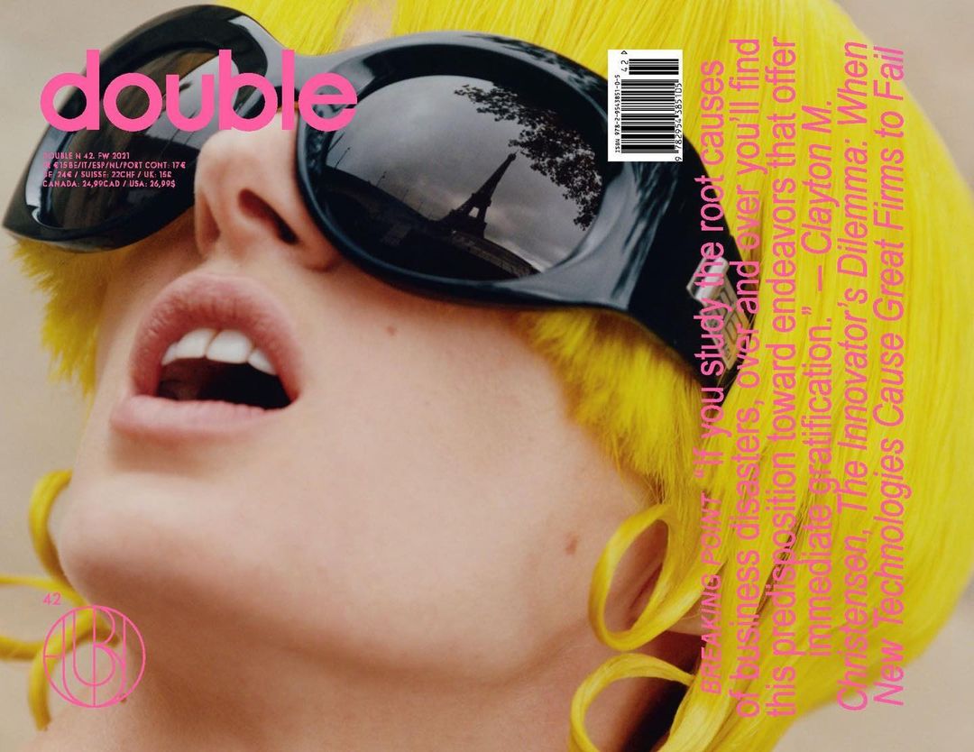 Magazine cover featuring a woman in sunglasses reflecting the Eiffel Tower, showcasing yellow hair and a distinctive design.