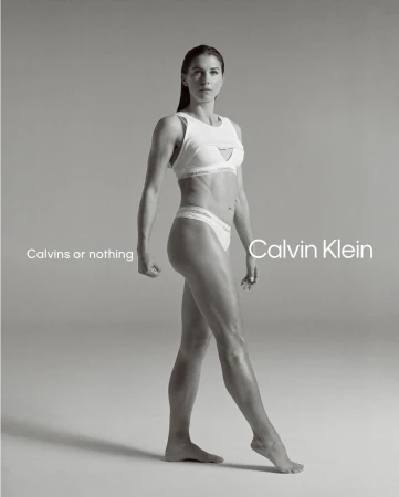 Alex Morgan standing against a seamless grey backdrop wearing white Calvin Klein athletic underwear and a matching sports bra.