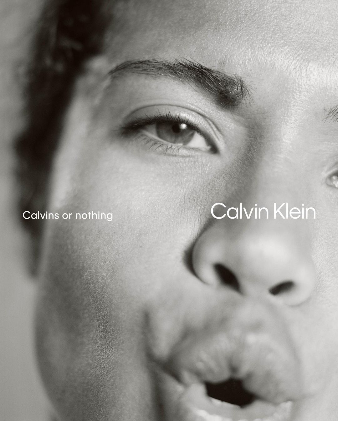 Close-up monochrome portrait of a person with puckered lips and dark eyebrows against a plain background.