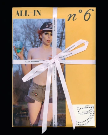 Person on package cover with cocktail glass, wearing hat and denim shorts, tied with ribbon and with number six visible.