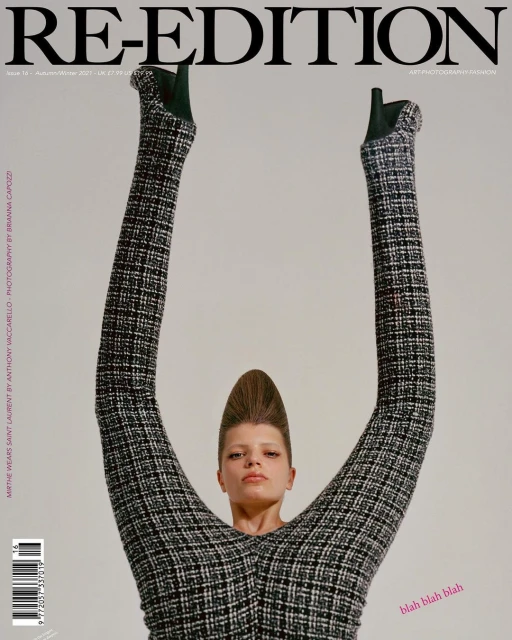 Magazine cover featuring a model in a tweed jumpsuit with legs raised overhead, showcasing unique fashion and editorial photography.