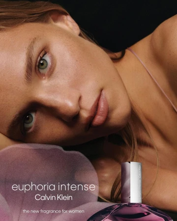 Close-up portrait of a woman with green eyes lying down, beside a purple perfume bottle for Calvin Klein Euphoria Intense.