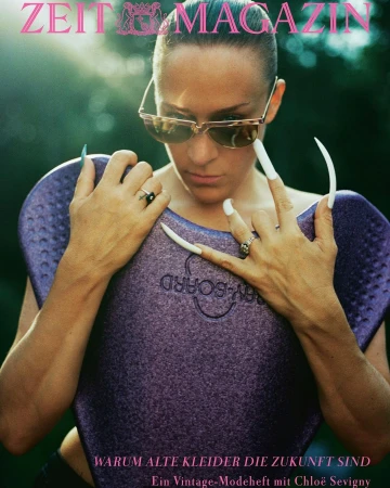 Fashion magazine cover featuring a woman wearing sunglasses and holding a purple bodyboard with extremely long white fingernails.