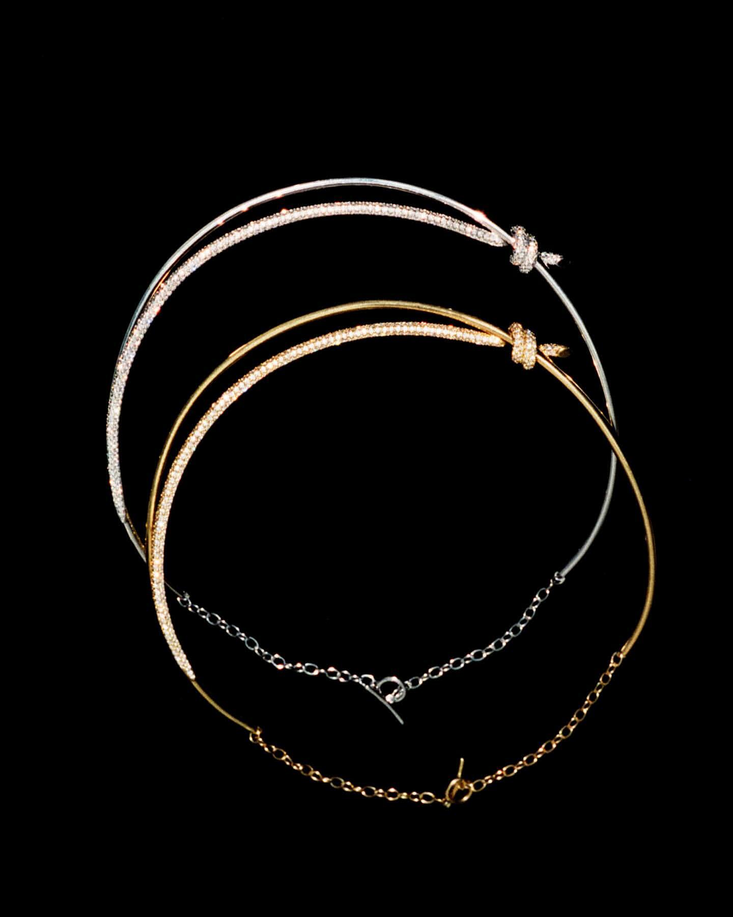 Two gold and silver necklaces are displayed against a black background, featuring intricate details and elegant designs, showcasing fashion jewelry.