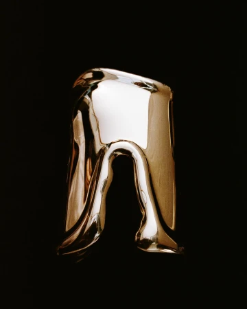 Abstract golden ring with flowing, melting design on a stark black backdrop, high contrast studio lighting, and reflective surface.