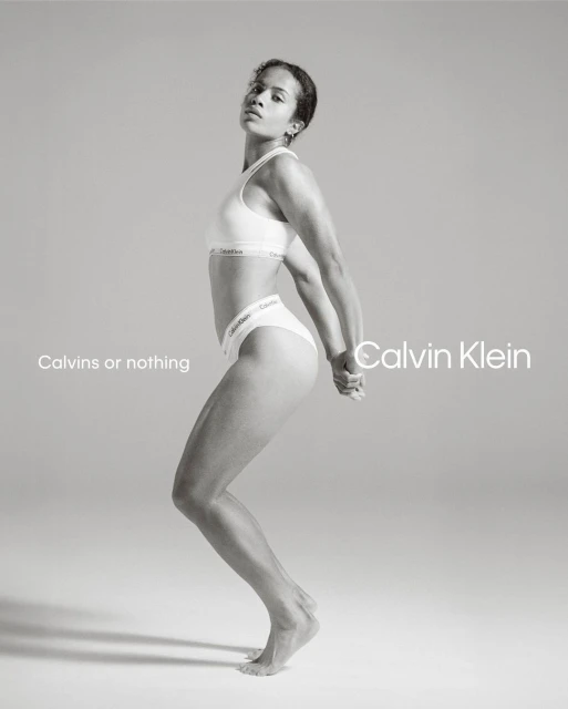 Athletic woman in Calvin Klein underwear strikes a pose in a bright studio. The photo is monochrome, featuring minimalist design elements.