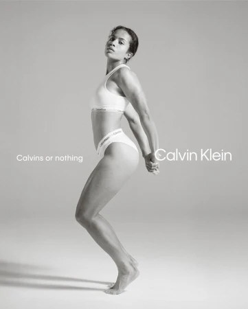Athletic woman in Calvin Klein underwear strikes a pose in a bright studio. The photo is monochrome, featuring minimalist design elements.