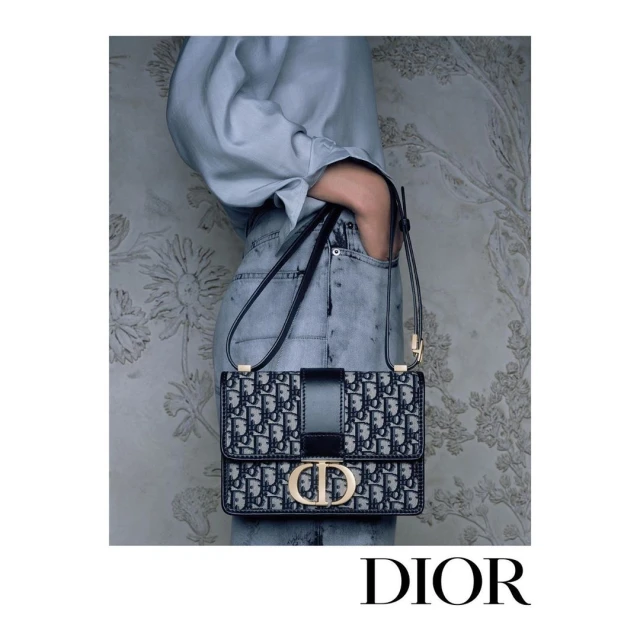 Fashion editorial featuring a woman in a light blue shirt and jeans with a black and white Dior handbag against a floral backdrop.