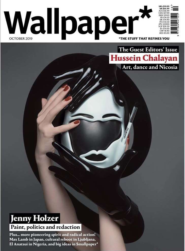 Wallpaper* magazine cover featuring a person in black gloves holding a black and white mask with the magazine logo and text.