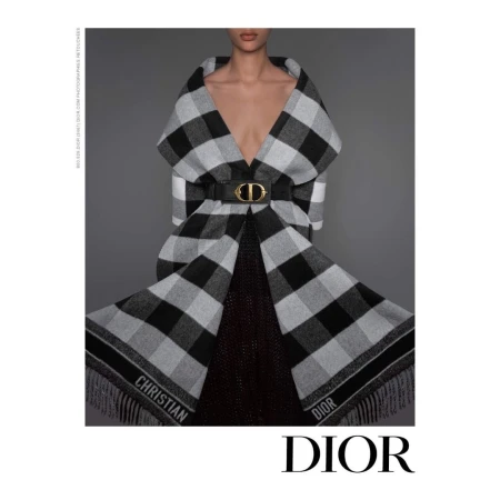 Model wearing a black and white plaid fringed coat belted with a large gold CD logo buckle by photographer Brigitte Niedermair