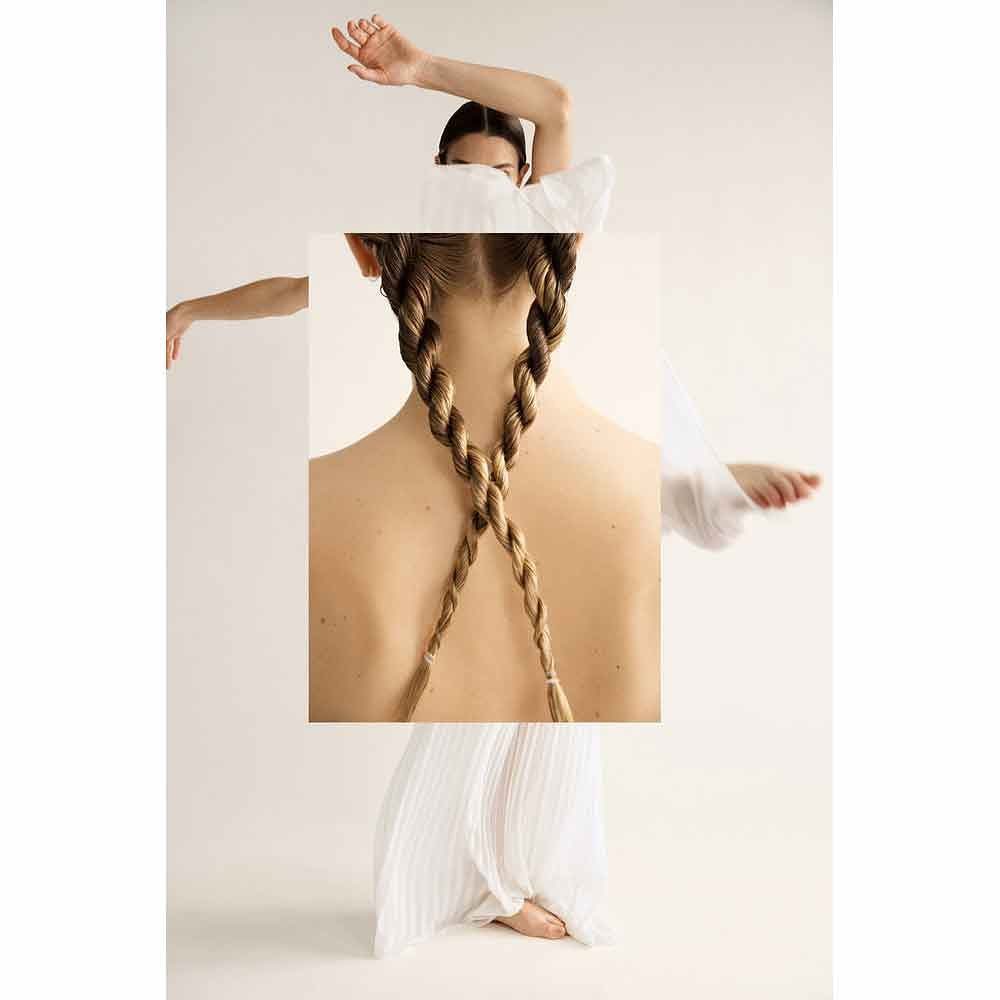 Back view of a person with two long braids against a white backdrop, showcasing hair, hair style, and minimalist aesthetic.