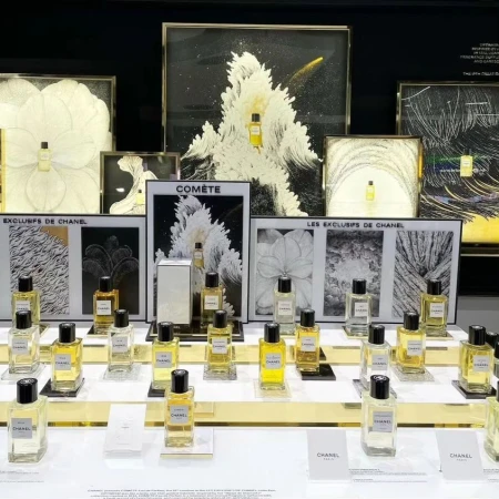 Display of Chanel perfume bottles behind framed pictures in a retail environment. The perfumes are evenly arranged on the shelves.