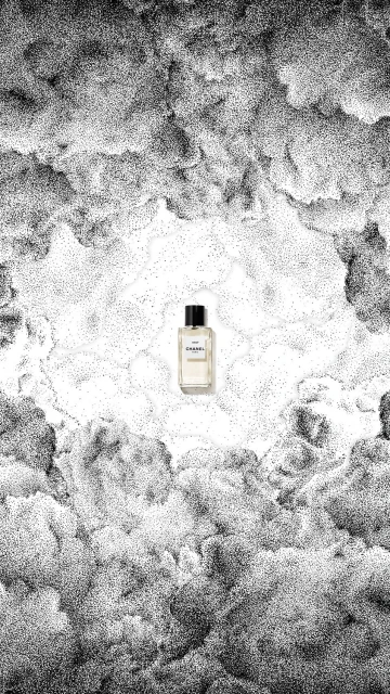 Artistic product shot: a perfume bottle stands against a stippled monochrome backdrop that mimics clouds and a celestial sky.