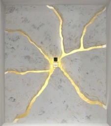 A perfume bottle sits at the center of cracked grey stone walls illuminated from behind by glowing yellow light.