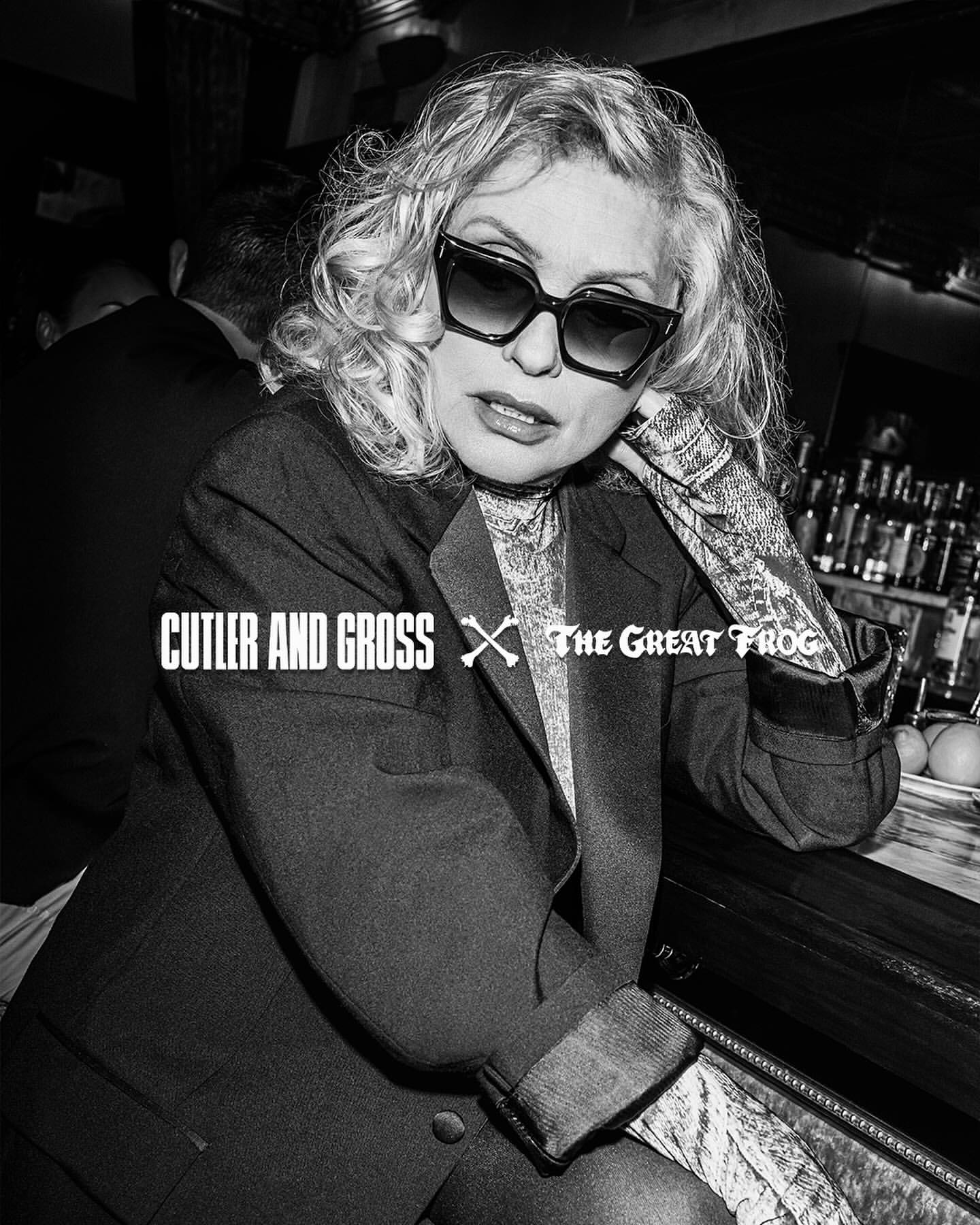 Black and white portrait of a blonde woman in sunglasses and a blazer, leaning against a bar, with logos for Cutler and Gross.