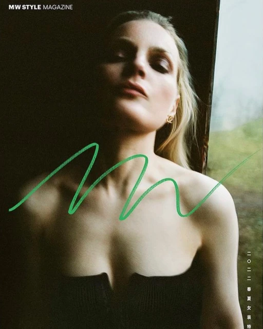 Close-up magazine cover shot of a blonde woman in a strapless top against a dark and blurred outdoor background.