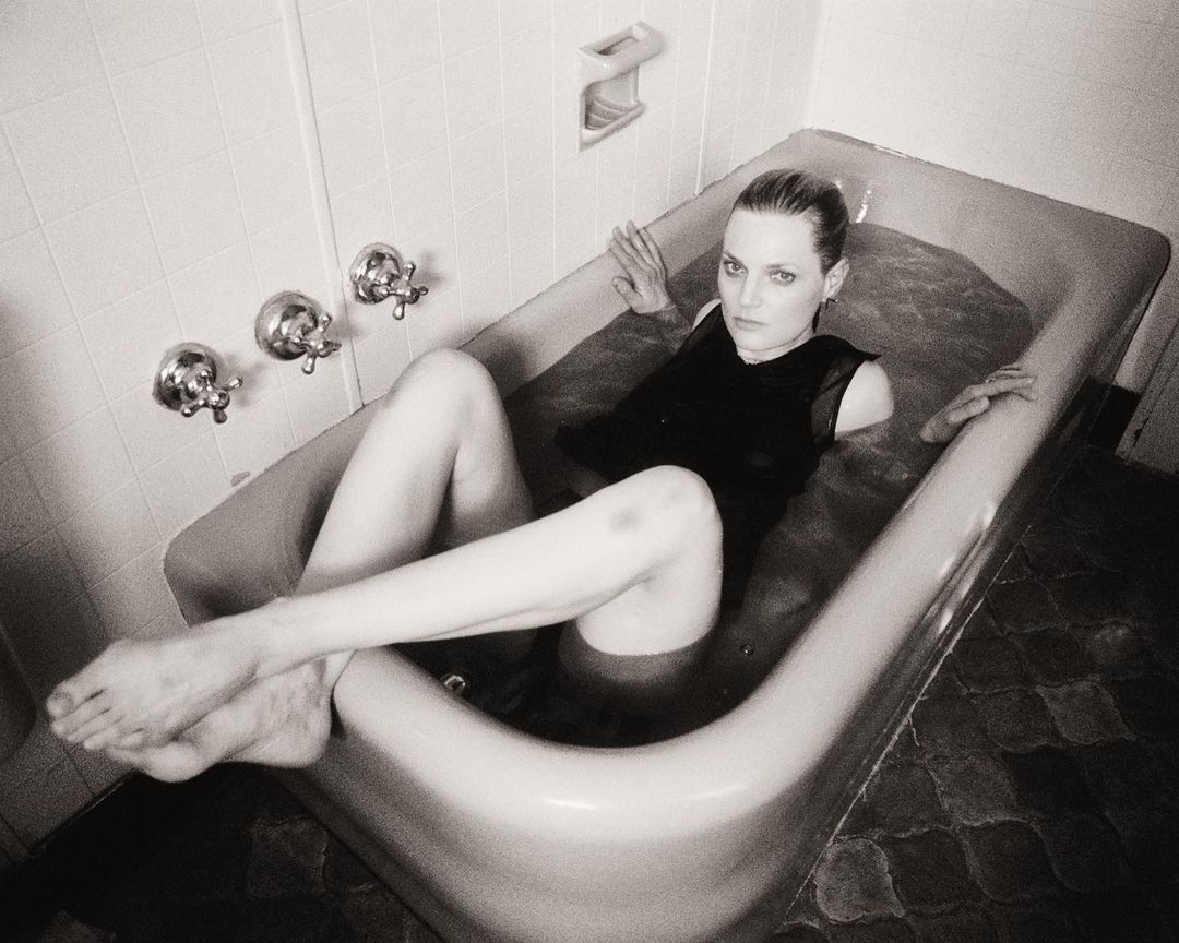 Black and white portrait of a woman in a bathtub wearing a dark top, photographed from a high angle by Bryan Liston.