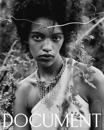 Monochrome portrait of a woman wearing an elaborate beaded necklace and white tank top framed by foliage by Bryan Liston
