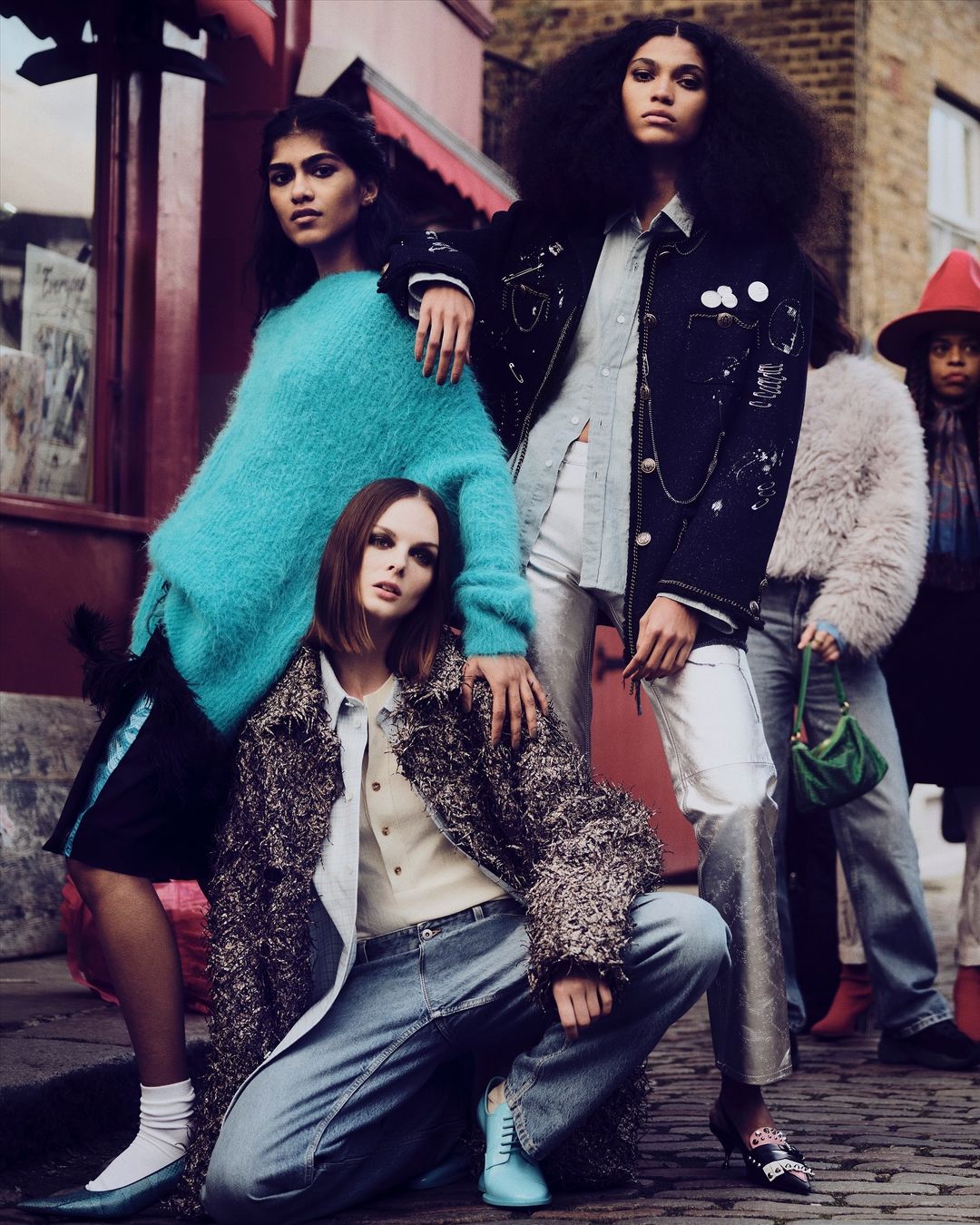 Group of five fashion models in stylish outerwear on a city street, posing with confidence and showcasing various textures and colors.
